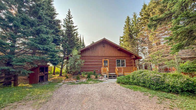 This charming log cabin retreat sits peacefully among towering pines and evergreens, offering a secluded mountain getaway with ample parking and natural surroundings to explore.