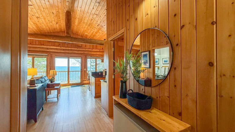 Step into your cozy wooden retreat with stunning lake views through expansive windows, where warm wood tones create the perfect lakeside escape.