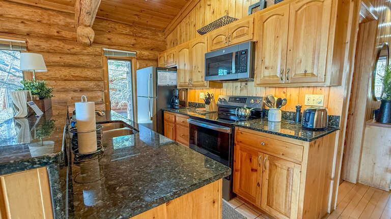 Step into your rustic cabin kitchen where granite countertops and warm wood create the perfect space for preparing mountain meals together.