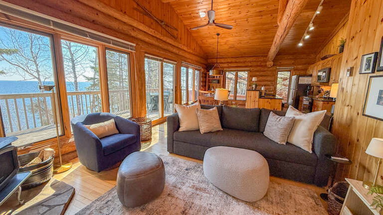 Unwind in your cozy log cabin living room where panoramic lake views and warm wood surround you in comfort.