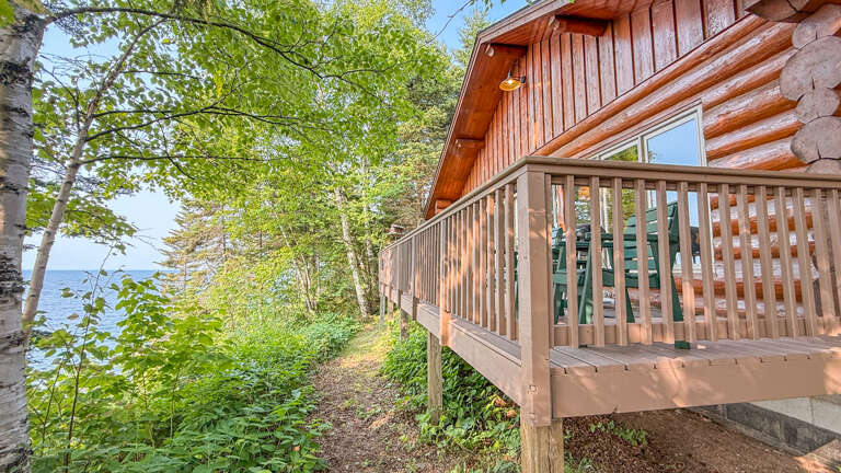 Charming lakeside cabin nestled among birch trees, with a private deck overlooking the water. The property offers direct access to nature trails and serene waterfront views.