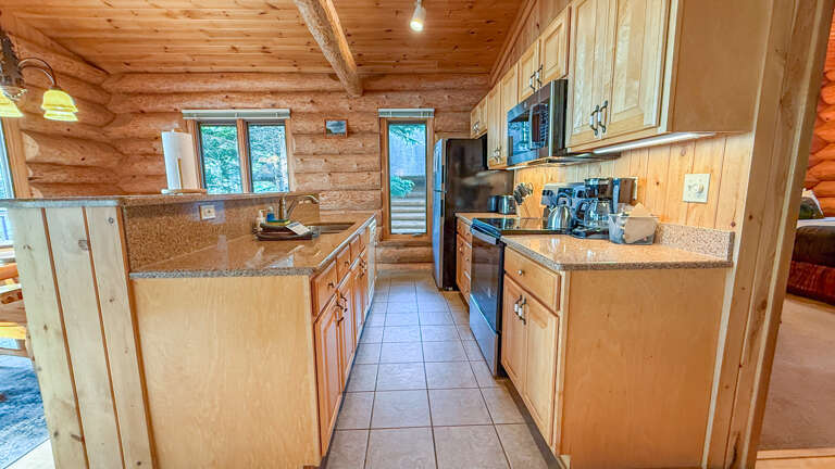 Your fully equipped kitchen awaits with granite countertops, modern appliances, and warm log cabin charmâperfect for preparing meals during your mountain getaway.
