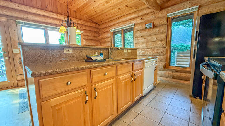 You'll find everything you need in this well-equipped kitchen, warmed by rustic log walls and bathed in natural light from large windows overlooking greenery.