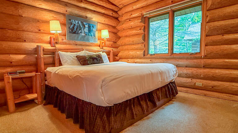 Unwind in your cozy log cabin bedroom where natural wood surrounds you with warmth. Drift off to sleep in the handcrafted log bed, bathed in soft lamp light after a day exploring the surrounding beauty.