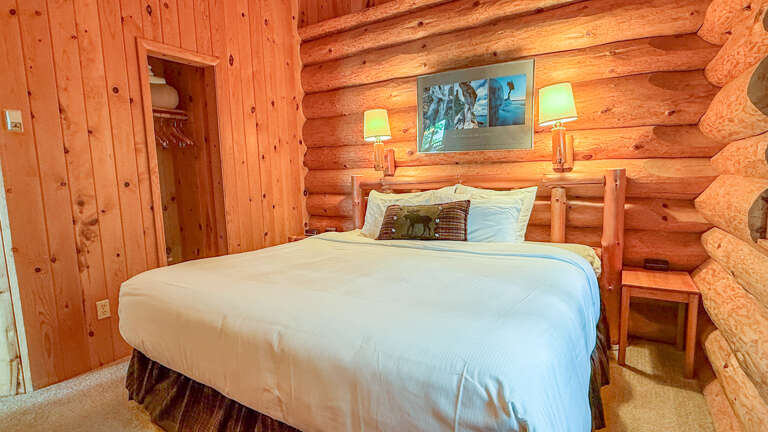 Unwind in your cozy log cabin bedroom, where rustic charm meets comfort. Sink into crisp linens, bask in the warm glow of bedside lamps, and let the natural wood surround you with peace.