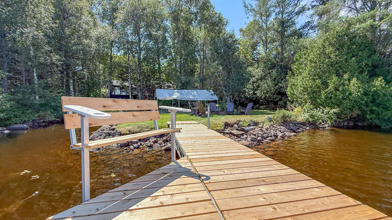 A private dock extends into calm waters, surrounded by mature trees and a natural shoreline. Perfect for fishing, kayaking, or simply watching the water drift by on a peaceful afternoon.