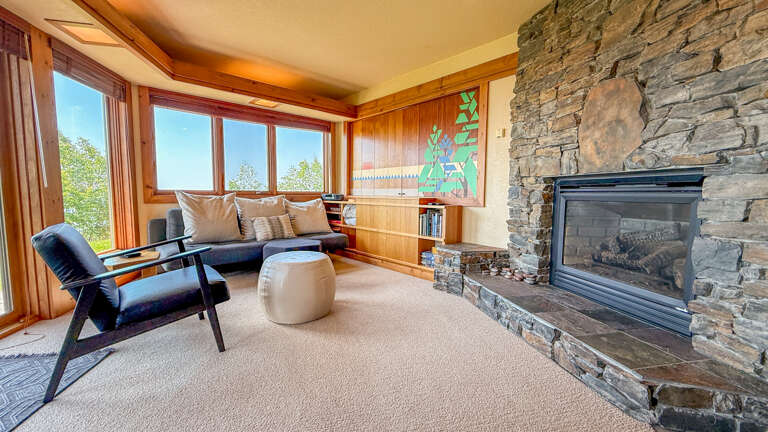 The living room has a stone-surround gas fireplace and a unique room divider that hides the TV. The living room has a stone-surround gas fireplace and a unique room divider that hides the TV.