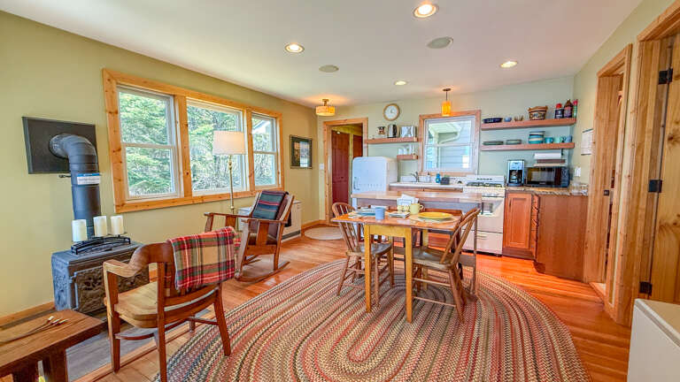 Your cozy retreat features a full kitchen, warm wood stove, and dining space where you'll share meals with loved ones surrounded by natural light and homey charm.