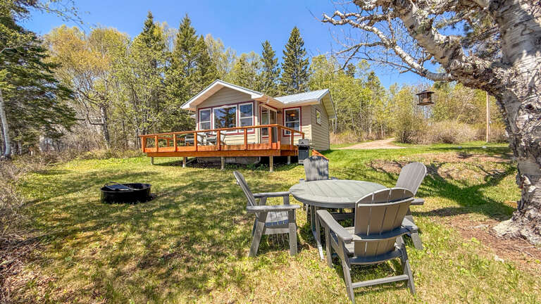 A cozy retreat nestled among aspen and evergreen trees with a spacious deck, fire pit, and backyard seating area surrounded by peaceful woodland scenery.