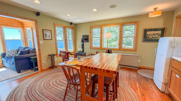 Gather for meals at your custom wood table while soaking in stunning lake views through bright windows. The open layout and warm pine accents create a welcoming space where every meal feels special.
