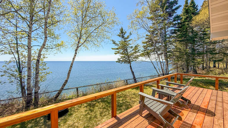 Lakefront deck overlooking calm waters framed by birch and evergreen trees. Perfect for morning coffee or evening sunsets.