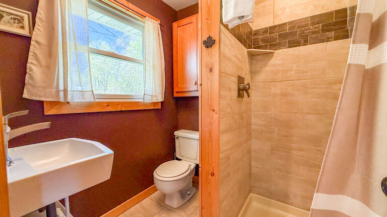 Your private bathroom features a spacious tiled shower, modern fixtures, and warm wood accents that create a cozy, cabin-like retreat after your daily adventures.