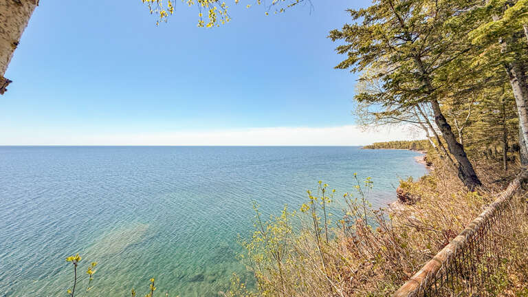 A stunning waterfront setting with crystal-clear turquoise waters and lush shoreline framing this peaceful retreat near the property.