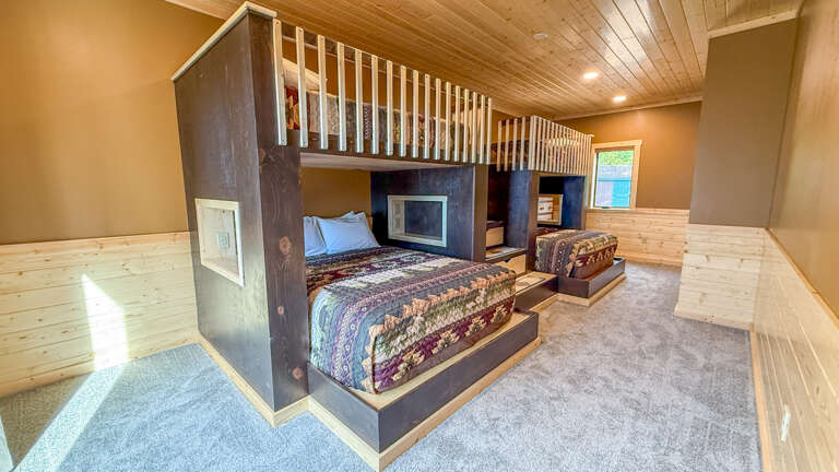 Your cozy retreat features custom-built bunk beds with plush bedding, warm wood accents, and a spacious loft perfect for families or groups seeking comfort together.