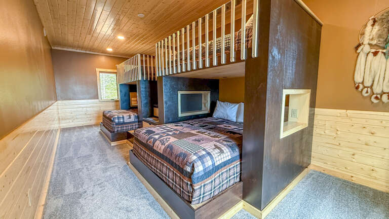 Cozy up in your spacious bunk room with plaid bedding, wood-paneled ceilings, and rustic charm. Perfect for families or friends seeking a warm, inviting retreat.