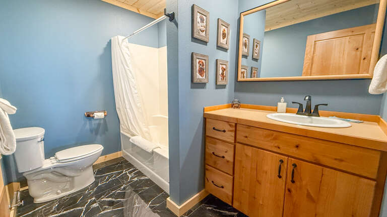 Freshen up in your private bathroom with elegant marble flooring, warm wood accents, and thoughtful touches like framed art and a well-stocked vanity ready for you.