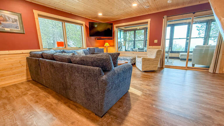 Sink into plush seating and unwind in your inviting living space, where warm wood tones and serene forest views create the perfect retreat for relaxation.
