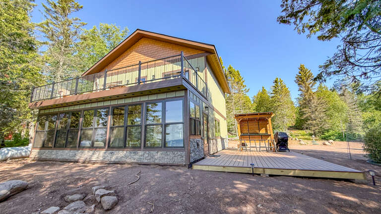 A charming lakeside property nestled among towering pines offers peaceful seclusion with private deck, hot tub, and abundant natural light from expansive windows framing the forest.