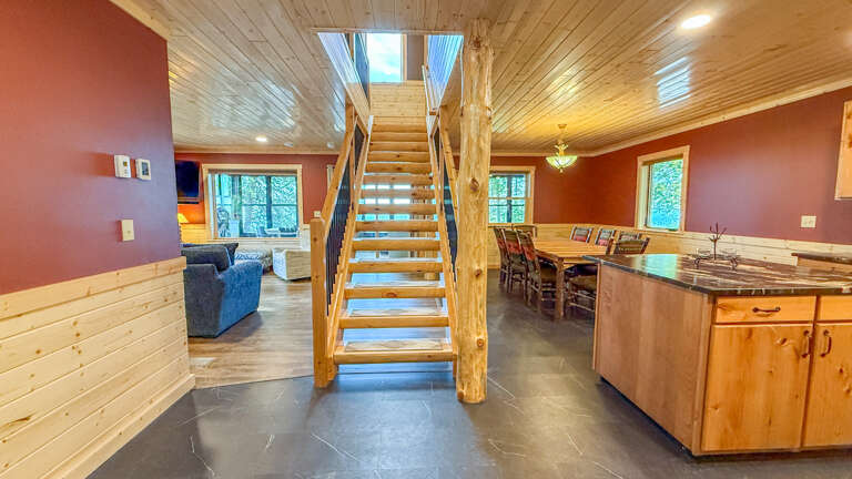 Step into this warm, open-concept cabin where rustic wood meets modern comfort. Natural light pours in through the skylight above the staircase, highlighting the spacious living and dining areas perfect for your mountain getaway.