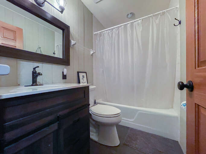 Freshen up in your private bathroom with a full tub-shower combo, sleek dark vanity, and fresh towels waiting. Everything you need for a relaxing stay.