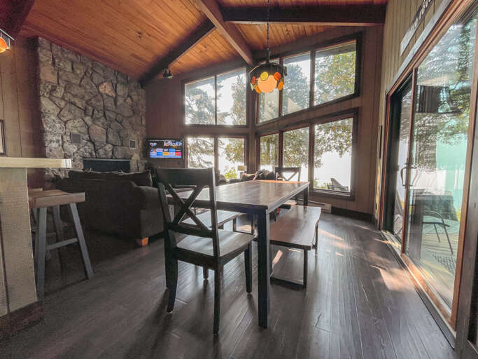 Gather around the cozy dining table where warm wood tones and natural light create the perfect setting for your morning coffee or family meals, with scenic forest views just beyond your windows.