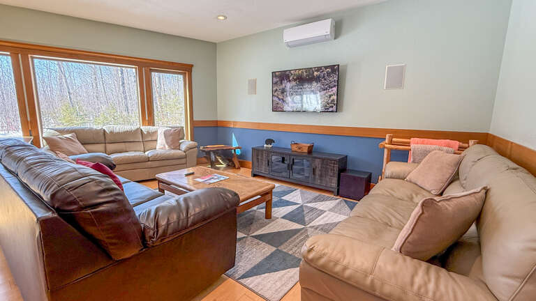 Sink into plush leather sofas in your spacious living room, where natural light streams through large windows and entertainment awaits on the wall-mounted TV.