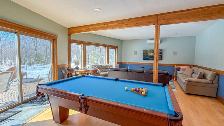 Your game room awaits with a professional pool table surrounded by cozy seating and winter views through the patio doors.