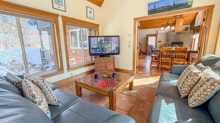 Relax in your spacious living room with plush leather seating, warm wood accents, and mountain views through expansive windows.