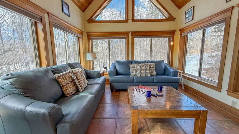 Sink into plush leather sofas while winter forest views surround you through floor-to-ceiling windows in this sunlit sanctuary.