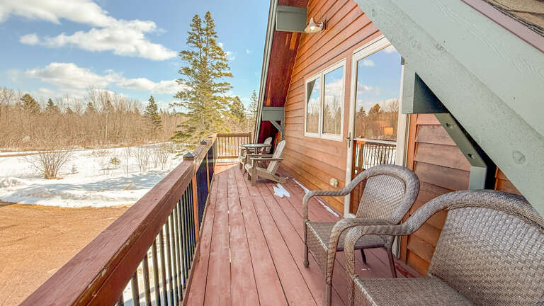 Step onto your private deck where winter wilderness meets comfort - cozy wicker chairs await for morning coffee with snowy forest views.
