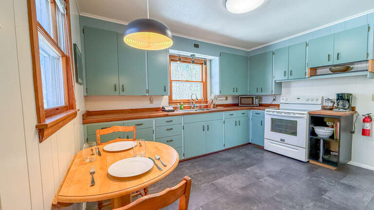 Your fully equipped kitchen features charming mint-green cabinets and warm wood countertops, perfect for preparing meals together.