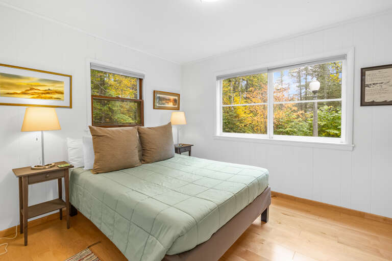 Wake up to vibrant autumn colors framing your window, inviting the warmth of natural light into your peaceful retreat. This cozy bedroom offers a restful escape where nature's beauty becomes part of your everyday experience.