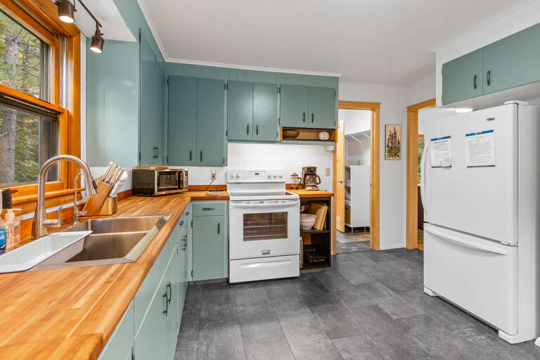 Charming kitchen with butcher-block countertops and sage green cabinetry where you can cook, gather, and feel right at home during your stay.