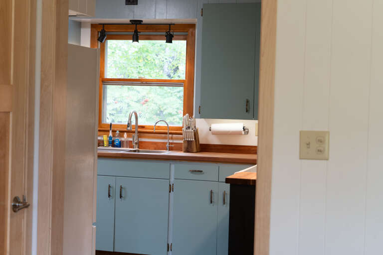 Step into your charming kitchen where vintage meets modern—blue-toned cabinets paired with warm wood countertops create a cozy space to whip up your morning coffee or family meals.