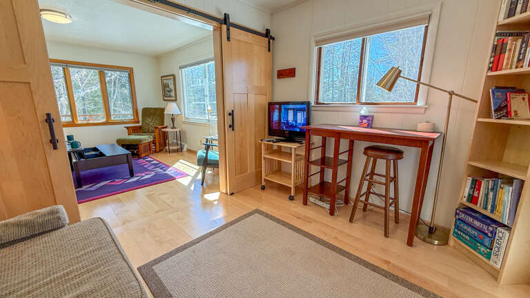 Unwind in your bright workspace with tall windows showcasing wooded views, a cozy reading nook, and thoughtful touches throughout.