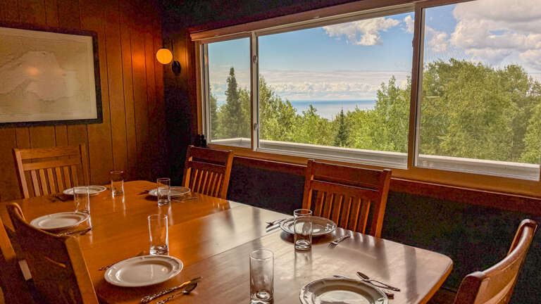 Gather around the warm wood dining table and savor your meals with sweeping views of tree-covered hills and the distant lake framed by floor-to-ceiling windows.
