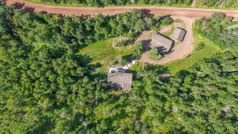 Aerial view of the property nestled in lush greenery with convenient parking and private access along a scenic country road.