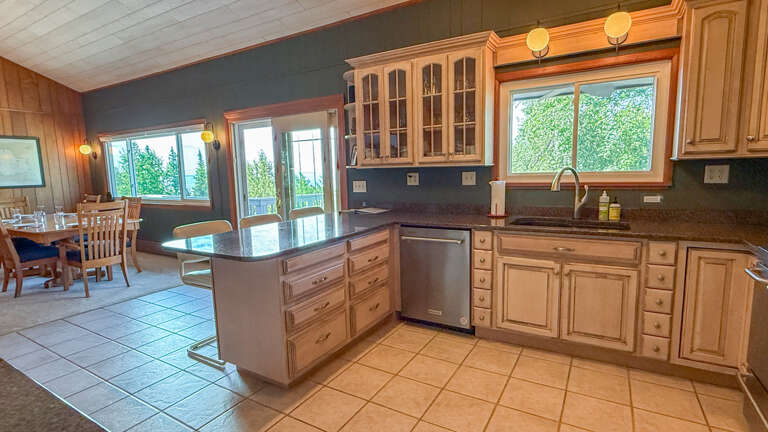 Your spacious kitchen and dining area flow seamlessly together, with warm wood cabinetry, generous counter space, and big windows framing the lush greenery outsideâperfect for cooking and gathering.