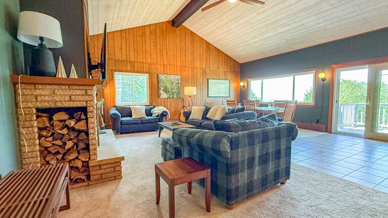 Spacious retreat with vaulted ceilings and abundant natural light. Cozy fireplace with stacked firewood, plush seating, and balcony access to peaceful surroundings.