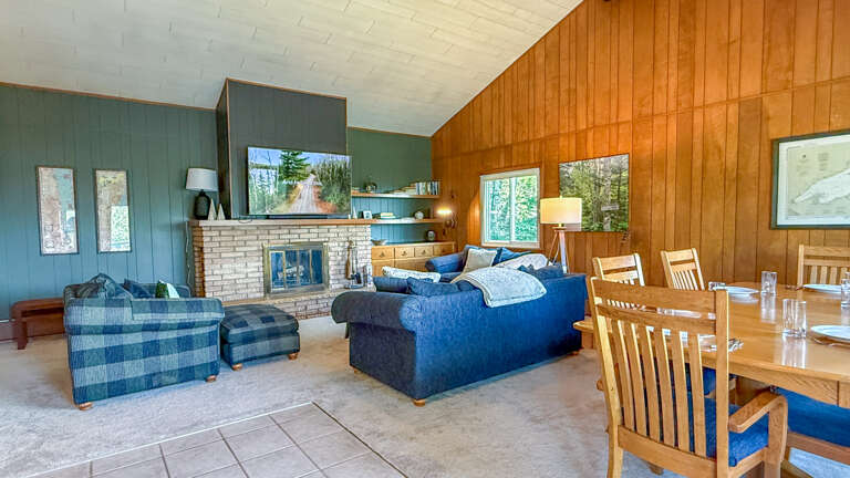 Step into your cozy cabin retreat with warm wood paneling, a stone fireplace, and plenty of natural light to make you feel right at home.
