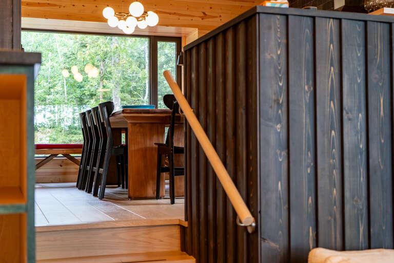 Natural light pours through large windows, framing your dining area with views of lush greenery. Warm wood tones and modern lighting create an inviting space for meals and conversation.