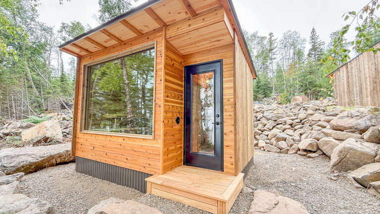 A modern tiny retreat tucked into a natural woodland setting, offering peace and privacy among towering trees and scenic rocky terrain.