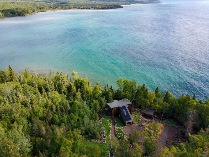 Waterfront retreat nestled along pristine turquoise waters, surrounded by lush forest and peaceful natural beauty.