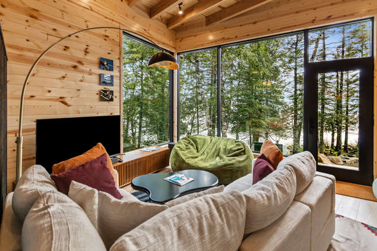 Sink into plush seating and let your eyes wander through floor-to-ceiling windows framing a serene forest. Warm wood beams and thoughtful touches make this your perfect retreat for unwinding.