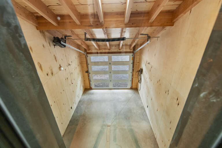 The property includes secure parking with a bright, well-constructed garage featuring exposed wood beams and polished concrete floors.
