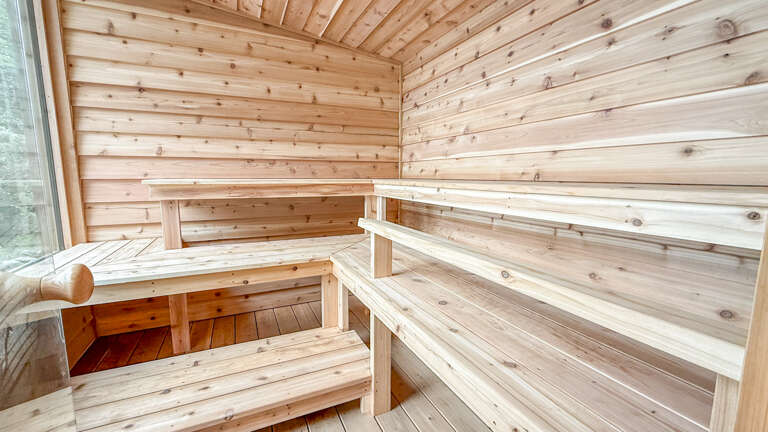 Step into this pristine wooden sauna where warm cedar walls and tiered benches invite you to unwind. Let the gentle heat melt away tension as you settle onto smooth, natural wood—your private wellness retreat awaits.