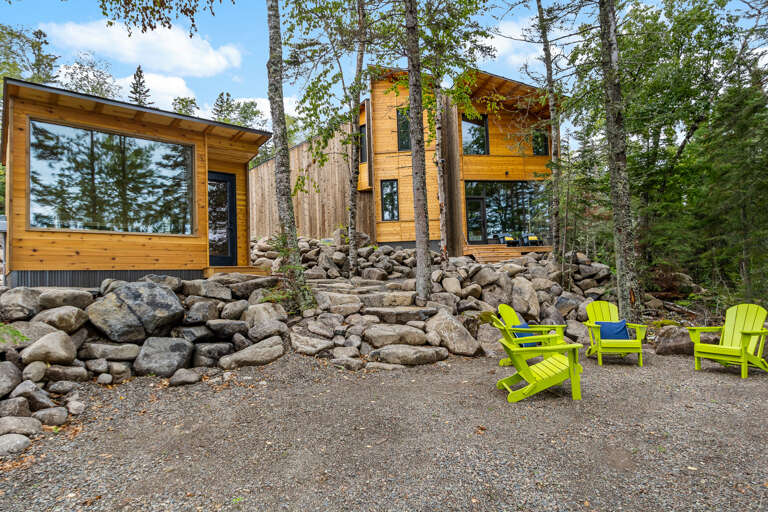 A modern cedar retreat nestled among towering pines and natural stone terracing, surrounded by forest tranquility and bright outdoor seating perfect for morning coffee or evening relaxation.