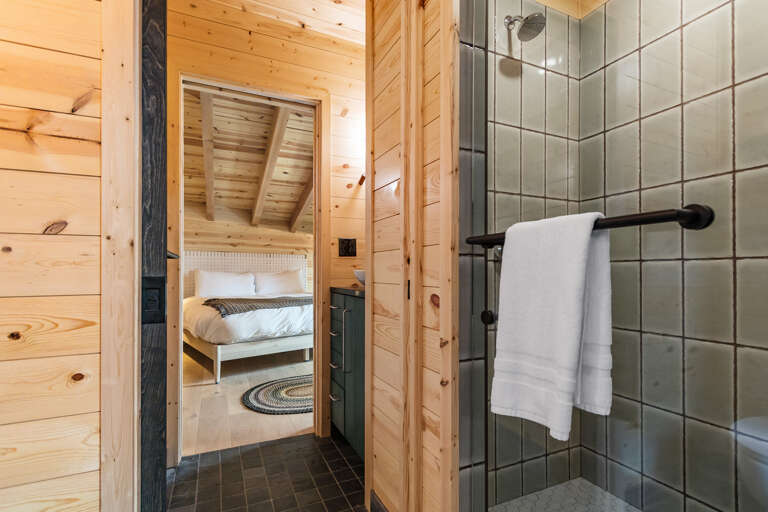Step into your cozy retreat—warm wood walls surround you, with a tiled shower ready to refresh you after a day of adventure and a peaceful bedroom just beyond.