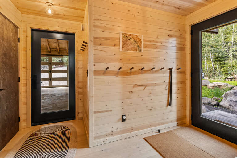 Bright pine walls and natural light from large windows create a welcoming entryway where you can unwind after your outdoor adventures, with hooks ready for your gear.