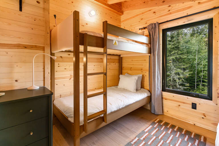 Drift off in this cozy bunk room where warm wood wraps around you and the forest whispers just outside your window—a perfect retreat for kids or friends sharing mountain memories.